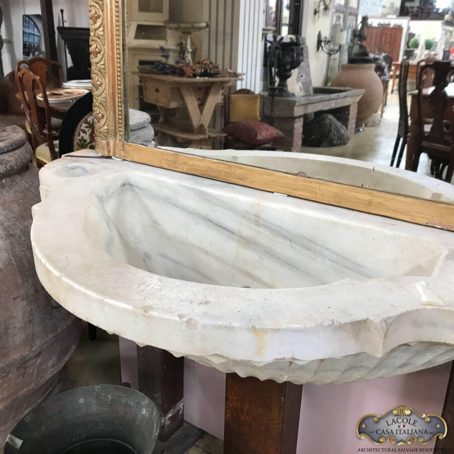 <h2>Antico lavandino in marmo</h2> Antico lavandino-fontana in marmo a forma mezzalauna, con forma a conchiglia